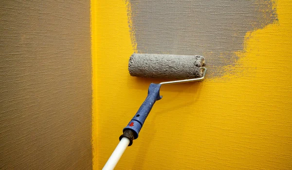 Feche o rolo com tinta cinza para pintar paredes. Reparos. Parede amarela. Contexto. Screensaver para o site. Fotografias De Stock Royalty-Free
