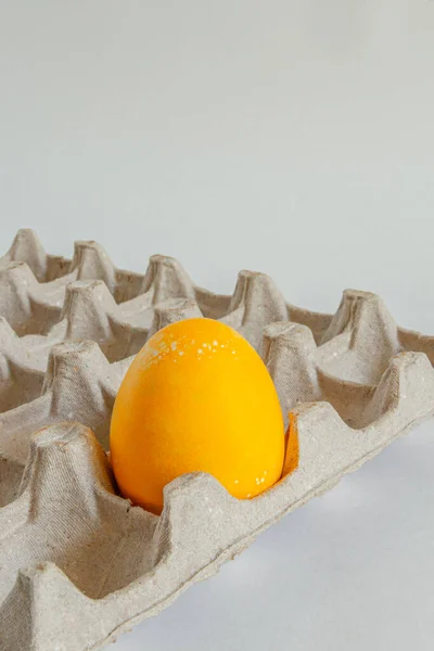 Um ovo amarelo numa caixa de cartão. Festa de Páscoa brilhante. Imagem De Stock