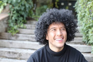 Dışarıdaki kıvırcık siyah saçlı yakışıklı genç adamın yakın plan portresi.