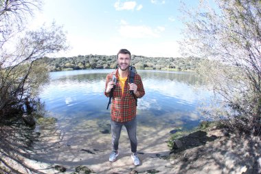 Doğada sırt çantalı, ekose gömlekli yakışıklı genç adamın portresi.