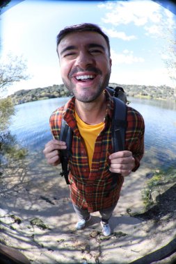 Doğada sırt çantalı, ekose gömlekli yakışıklı genç adamın portresi.