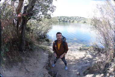 Doğada sırt çantalı, ekose gömlekli yakışıklı genç adamın portresi.