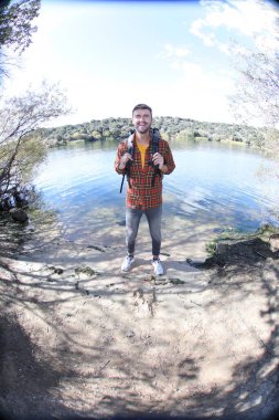 Doğada sırt çantalı, ekose gömlekli yakışıklı genç adamın portresi.