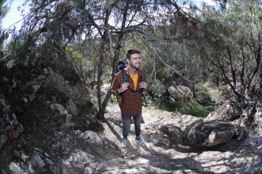 Doğada sırt çantalı, ekose gömlekli yakışıklı genç adamın portresi.