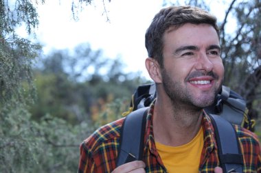 Doğada sırt çantalı, ekose gömlekli yakışıklı genç adamın portresi.