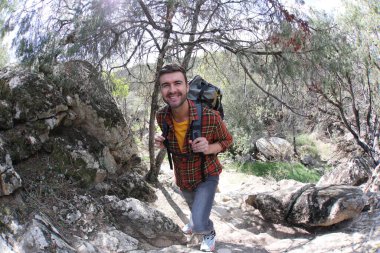 Doğada sırt çantalı, ekose gömlekli yakışıklı genç adamın portresi.