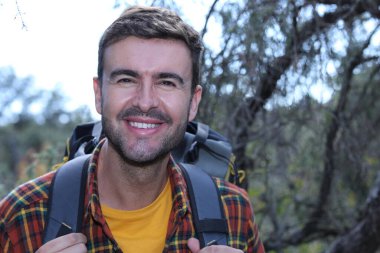 Doğada sırt çantalı, ekose gömlekli yakışıklı genç adamın portresi.