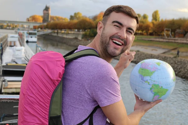 旅行者のバックパックを持つハンサムな若い男の肖像画川で地球を保持 — ストック写真