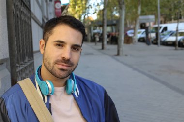 Şehir sokaklarında kulaklıklı, şık giyinmiş yakışıklı genç bir adamın portresi.
