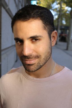 Şehir caddesinde şık pembe tişörtlü yakışıklı genç bir adamın portresi.