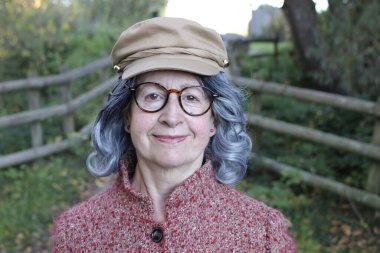 Açık havada gri saçlı yaşlı bir kadının portresi.