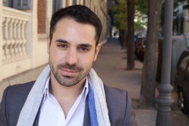 Şehir caddesinde atkısı olan ceketli ve gömlekli yakışıklı genç adamın portresi.