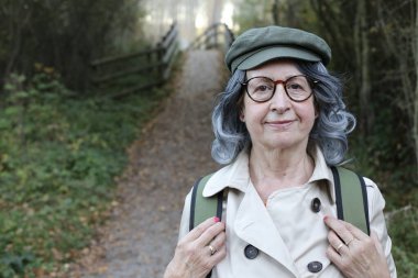 Açık havada gri saçlı yaşlı bir kadının portresi.