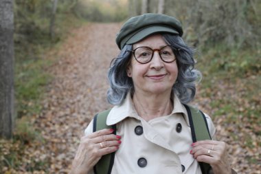 Açık havada gri saçlı yaşlı bir kadının portresi.