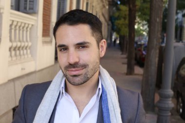 Şehir caddesinde atkısı olan ceketli ve gömlekli yakışıklı genç adamın portresi.