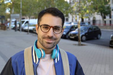 Şehir sokaklarında kulaklıklı, şık giyinmiş yakışıklı genç bir adamın portresi.