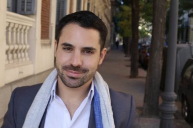 Şehir caddesinde atkısı olan ceketli ve gömlekli yakışıklı genç adamın portresi.