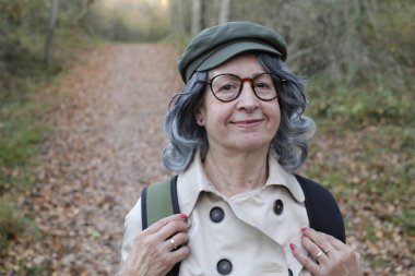 Açık havada gri saçlı yaşlı bir kadının portresi.