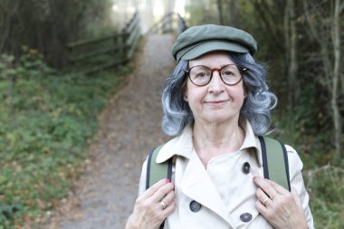 Açık havada gri saçlı yaşlı bir kadının portresi.