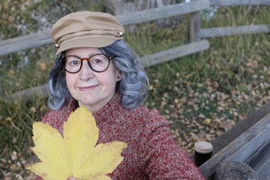 Açık havada gri saçlı yaşlı bir kadının portresi.