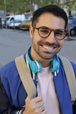 Şehir sokaklarında kulaklıklı, şık giyinmiş yakışıklı genç bir adamın portresi.