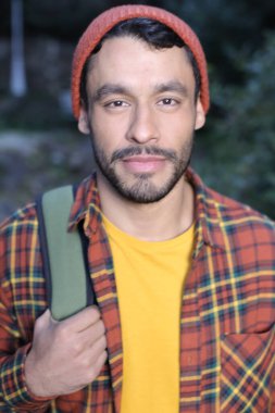 Sırt çantalı, kırmızı ekose gömlekli yakışıklı genç adamın yakın plan portresi.