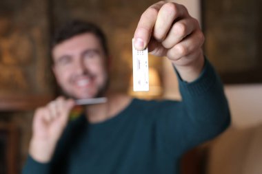 Evinde hızlı test yapan yakışıklı genç adamın yakın plan portresi.