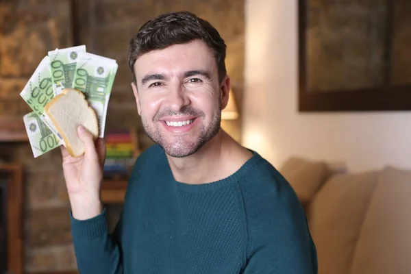 家でユーロ紙幣でサンドイッチを持っているハンサムな若い男のクローズアップ肖像画 — ストック写真