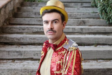 Parktaki merdivenlerin önünde renkli bir sirk elbisesi içinde yakışıklı bir genç portresi.