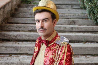 Parktaki merdivenlerin önünde renkli bir sirk elbisesi içinde yakışıklı bir genç portresi.