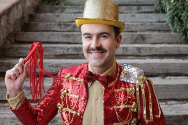 Parktaki merdivenlerin önünde renkli bir sirk elbisesi içinde yakışıklı bir genç portresi.