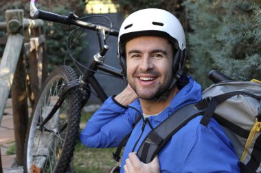 portrait of handsome young man with helmet and bicycle on nature