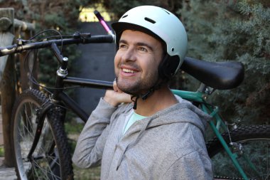 portrait of handsome young man with helmet and bicycle on nature