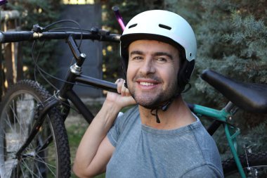 portrait of handsome young man with helmet and bicycle on nature