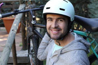 portrait of handsome young man with helmet and bicycle on nature