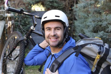 portrait of handsome young man with helmet and bicycle on nature