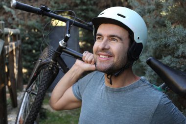 portrait of handsome young man with helmet and bicycle on nature