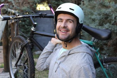 portrait of handsome young man with helmet and bicycle on nature