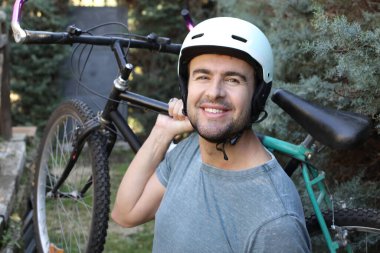 portrait of handsome young man with helmet and bicycle on nature