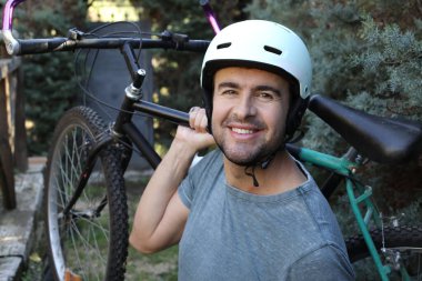portrait of handsome young man with helmet and bicycle on nature