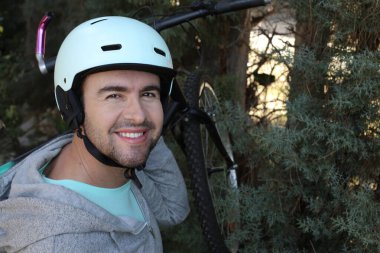 portrait of handsome young man with helmet and bicycle on nature