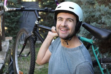 portrait of handsome young man with helmet and bicycle on nature