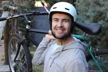 portrait of handsome young man with helmet and bicycle on nature