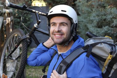 portrait of handsome young man with helmet and bicycle on nature