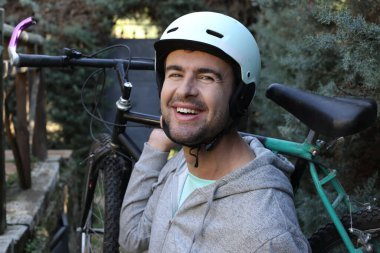 portrait of handsome young man with helmet and bicycle on nature