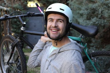 portrait of handsome young man with helmet and bicycle on nature