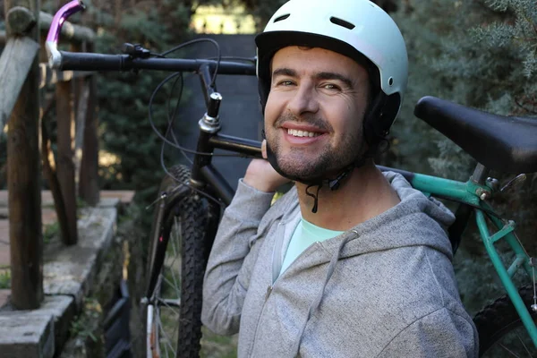 portrait of handsome young man with helmet and bicycle on nature
