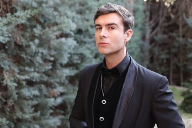 Yakından çekilmiş siyah takım elbiseli yakışıklı genç adam portresi.