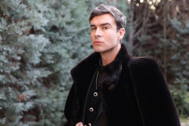 Siyah kürklü ve takım elbiseli yakışıklı genç adamın yakın plan portresi.