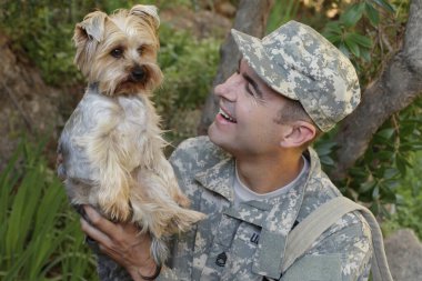 Yakışıklı genç askerin yakın plan portresi ve sevimli bir köpek yavrusu.